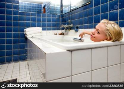 A woman in an old 20s style spa soaking in a bath tub