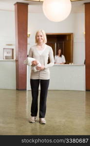 A woman in an old style spa reception with towel in hand.