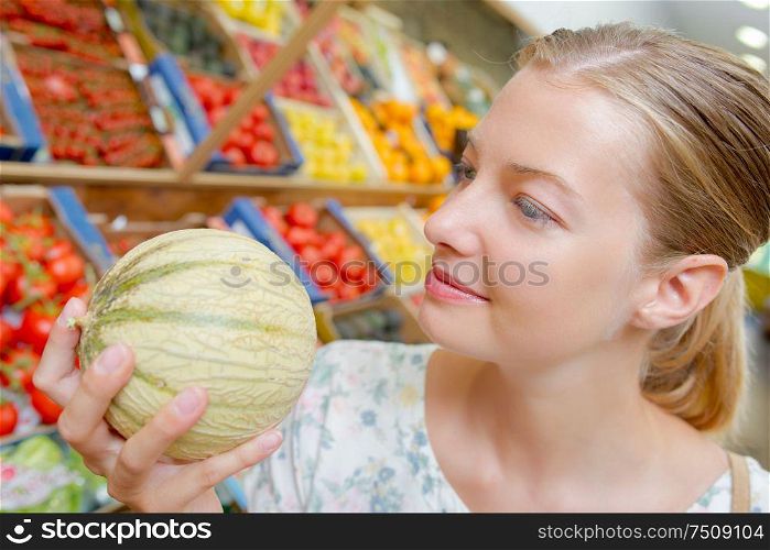 a woman is buying melon