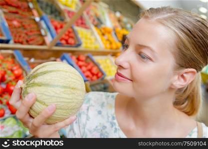 a woman is buying melon
