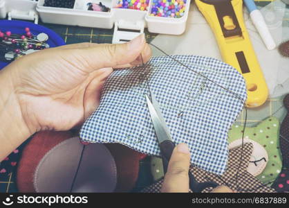 A woman is doing needlework with other embroidery equipment on a table