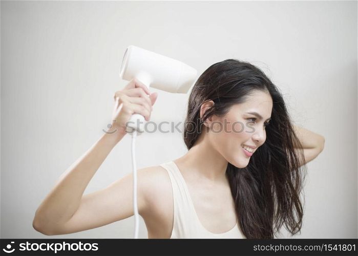 A woman is drying her hair after showering