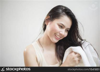 A woman is drying her hair with a towel after showering
