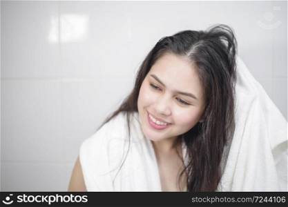 A woman is drying her hair with a towel after showering