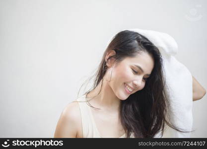 A woman is drying her hair with a towel after showering