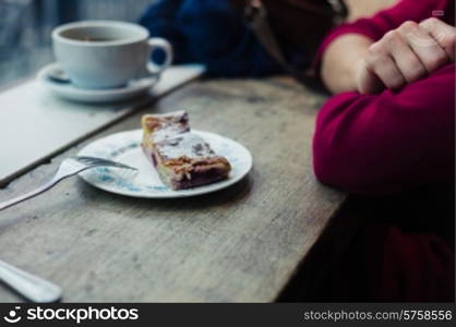 A woman is having coffee and cake by a window in a cafe