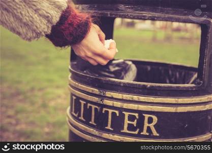 A woman is throwing something in a litter bin at the park