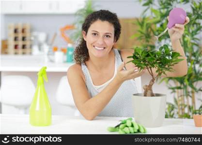 a woman is watering a bonsai
