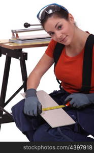 A woman measuring a tile before cutting it.