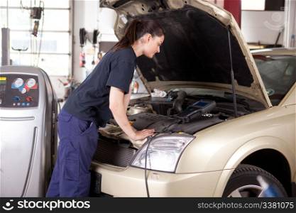 A woman mechanic tuning a car with diagnostic equipment