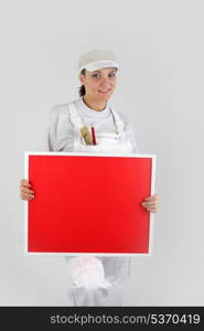 A woman painter holding up a red board