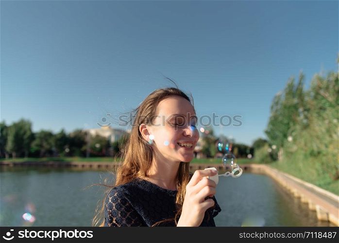 A woman picnic in the park wearing beautiful long blue dress siting with a book in her hand. Young woman in blue dress reads a book at a picnic in the park .Cozy picnic of summer day.