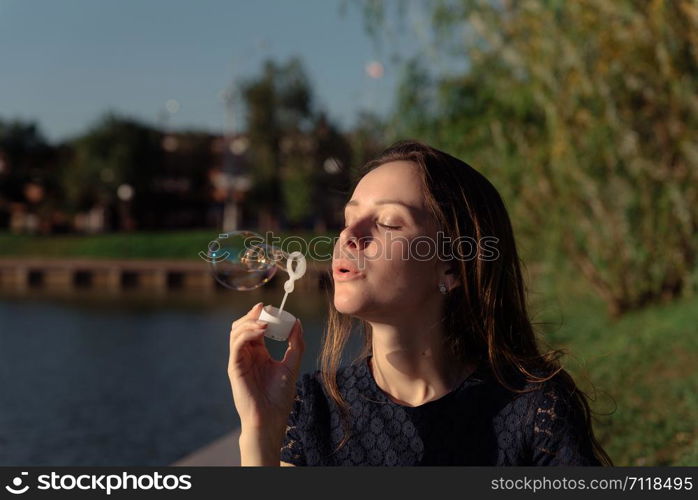 A woman picnic in the park wearing beautiful long blue dress siting with a book in her hand. Young woman in blue dress reads a book at a picnic in the park .Cozy picnic of summer day.