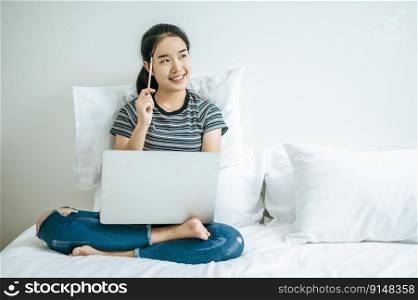 A woman playing laptop Hold a pencil and smile happily.