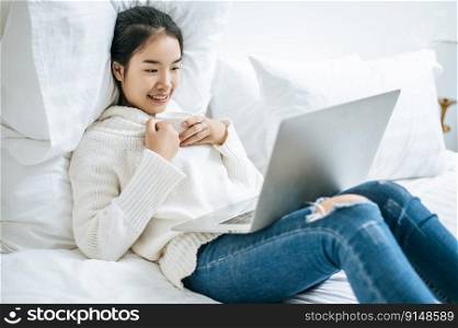 A woman playing laptop Take a cup of coffee and smile happily.