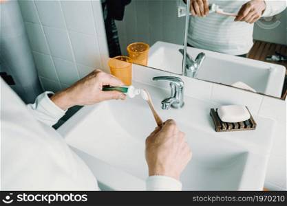 A woman puts teeth cream on his bamboo toothbrush