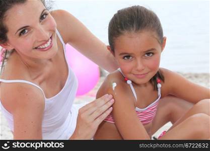 A woman putting suncream on her daughter.