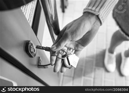 A woman&rsquo;s hand opens the door with a key on which the keychain hangs at home. A woman&rsquo;s hand opens the door with a key on which the keychain hangs at home.