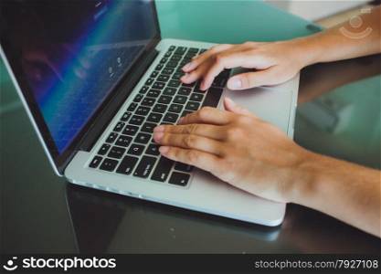 A woman&rsquo;s hands are typing on a laptop computer keyboard. The monitor is visible in the image, but it is not clear what she is working on.