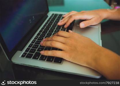 A woman&rsquo;s hands are typing on a laptop computer keyboard. The monitor is visible in the image, but it is not clear what she is working on.