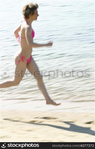 A woman running along the beach. Fun free happy.