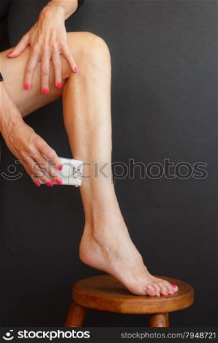 a woman shaving her legs stretching the skin with your hands and put your foot on the stool