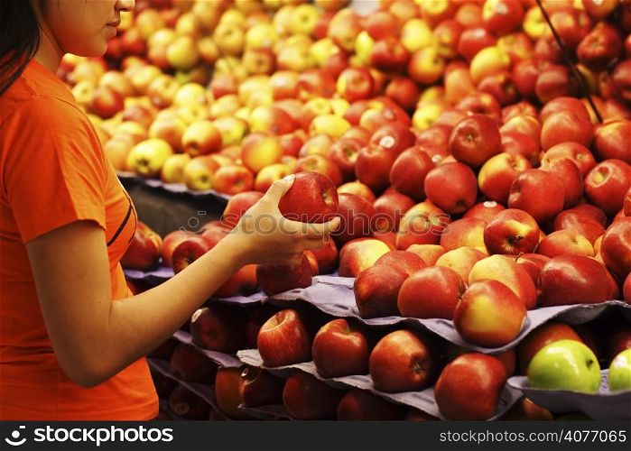A woman shopping for apples at a grocery store