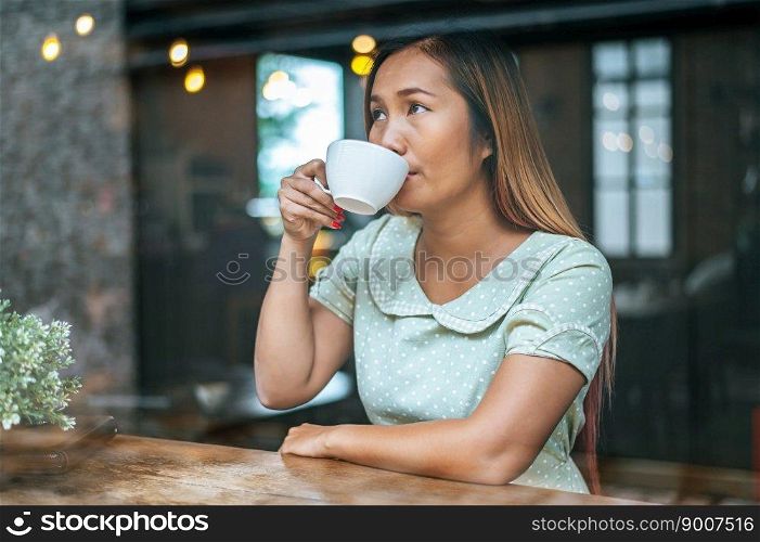 A woman sitting and drinking coffee in a coffee shop