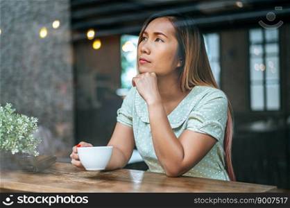 A woman sitting and drinking coffee in a coffee shop