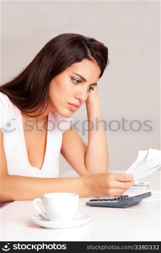 A woman sitting at a desk with calculator and papers planning a budget