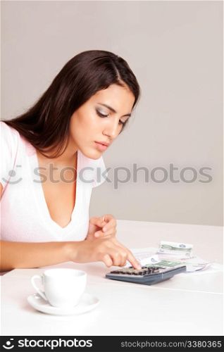 A woman sitting at a table with calculator, papers and coffee cup