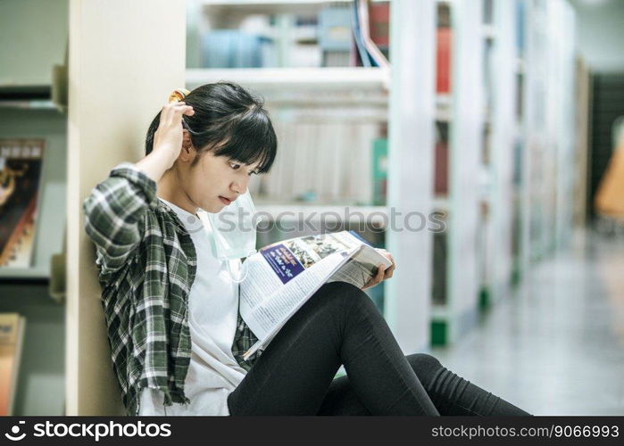 A woman sitting reading a book in the library.