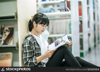 A woman sitting reading a book in the library.