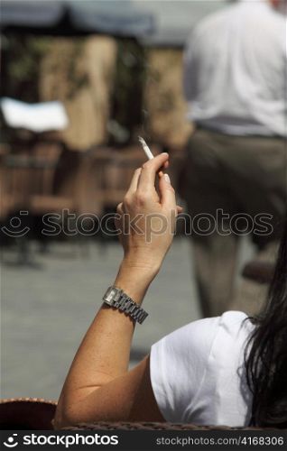 A woman smoking while relaxing at a pavement cafe.
