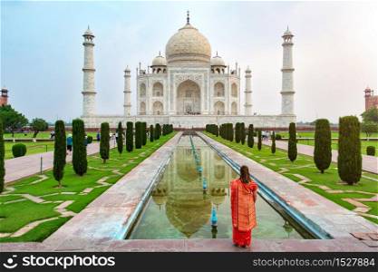 A woman standing front of Taj Mahal, an ivory-white marble mausoleum on the south bank of the Yamuna river in Agra, Uttar Pradesh, India. One of the seven wonders of the world.. A woman standing front of Taj Mahal.