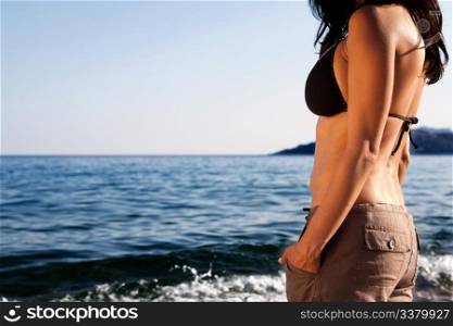 A woman standing on the beach looking out at the horizon
