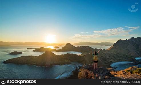 A woman standing on the peak of Padar Island in sunset time, Komodo Nation Park, Indonesia.. A woman standing on the peak of Padar Island in sunset time.