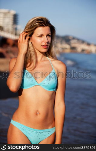 A woman walking along the beach with city in the background