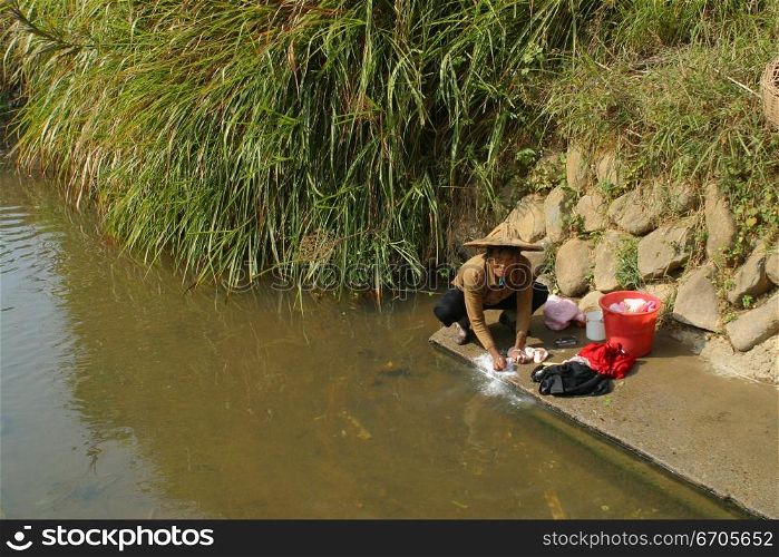 A woman washes her clothing in a river in China.