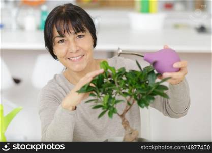 a woman watering bonsai tree