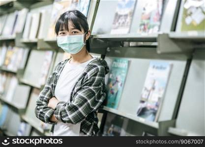 A woman wearing a mask and searching for books in the library.