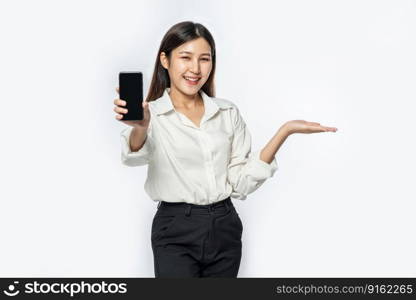 A woman wearing a shirt and holding a smartphone stretched forward.