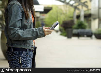 A woman with a cellphone in an outdoor shopping mall