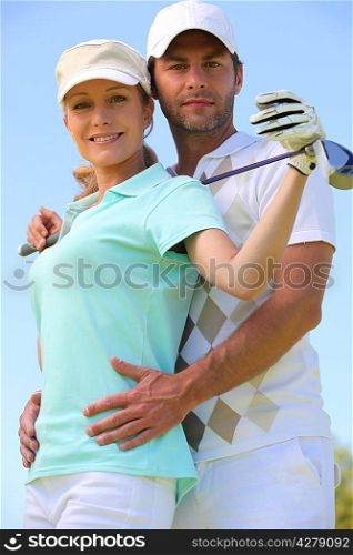 a woman with a golf club and a man putting his hands on her waist