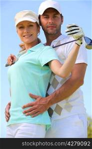 a woman with a golf club and a man putting his hands on her waist