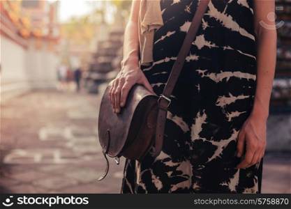 A woman with a handbag is standing in the grounds of a buddhist temple