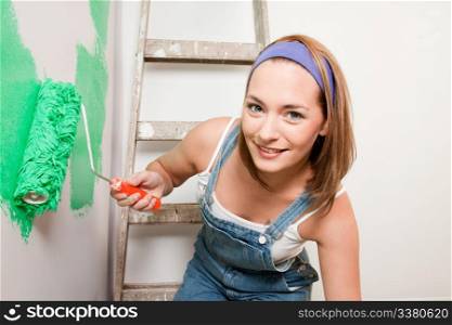 A woman with a paint roller, painting a home interior