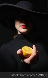 A Woman With Red Lips In A Black Hat holding half lemon