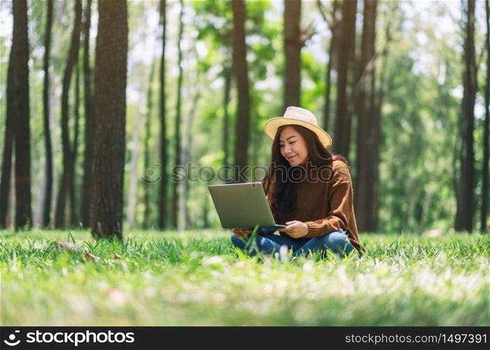A woman working and typing on laptop keyboard while sitting in the park