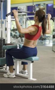 A woman works out at a back station in a heath and fitness center